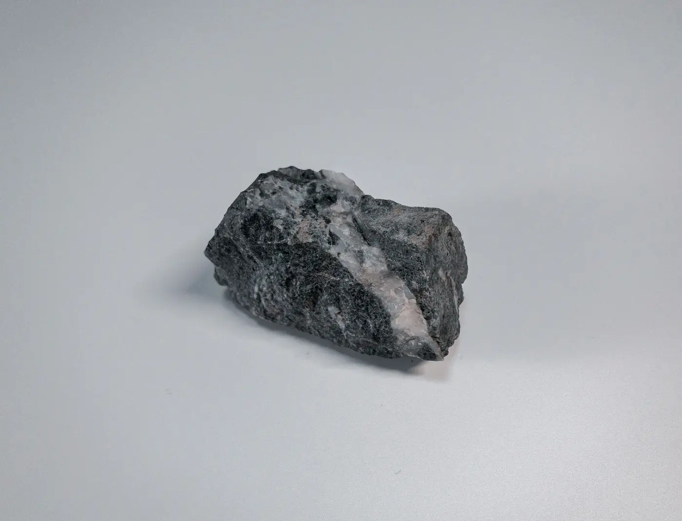 Close-up of a dark metallic ore sample on a light surface